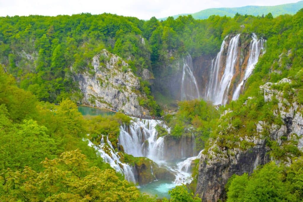 An overhead view of cascading waterfalls and lakes surrounded by lush greenery at Plitvice Lakes National Park in Croatia