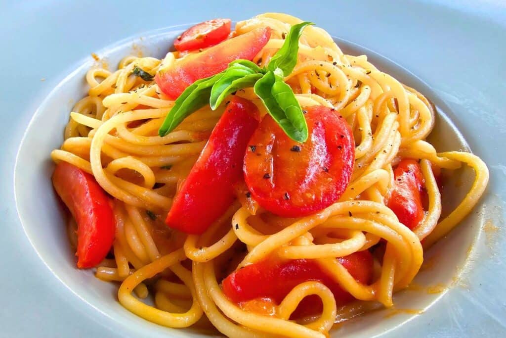 Spaghetti pasta with cherry tomatoes and a sprig of basil in Syros Greece