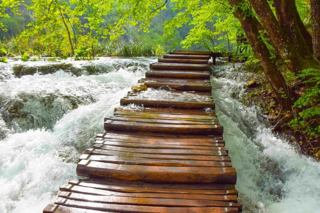 A nearly submerged wooden walking path across the rushing waters of Plitvice Lakes National Park in Croatia