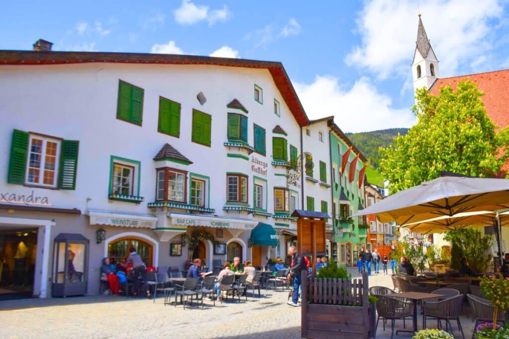 Colorful alpine guesthouses line a cobbled street in Italy's Dolomites region