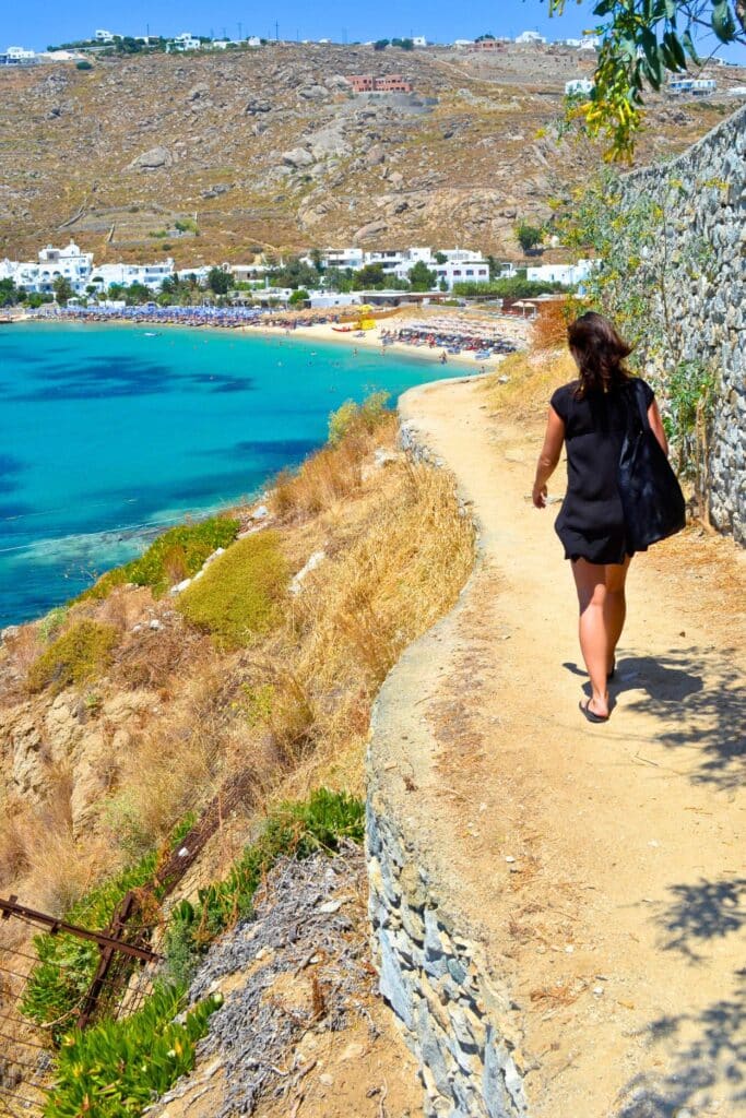 A cliffside path leading down to a white sand beach on Mykonos islands